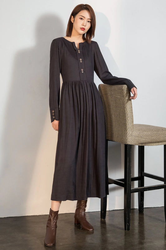 May include: A long-sleeved, dark gray dress with a button-up front and a gathered skirt. The dress has a v-neck and is worn with brown ankle boots.