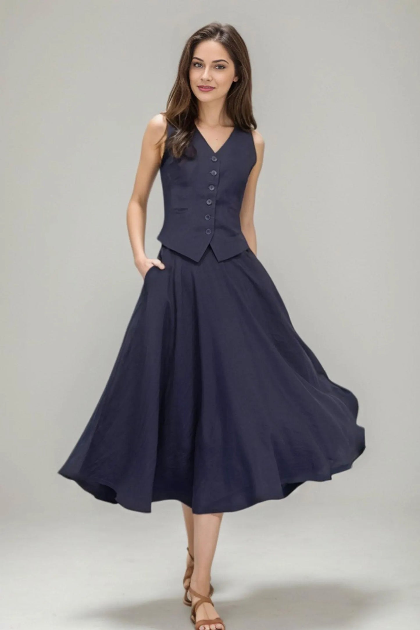 May include: A navy blue sleeveless vest with buttons and a matching navy blue midi skirt with pockets.