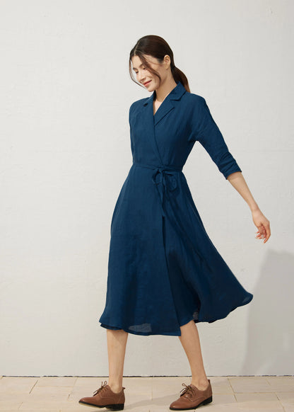 Model wearing navy blue linen midi wrap dress with notched collar and flared hem